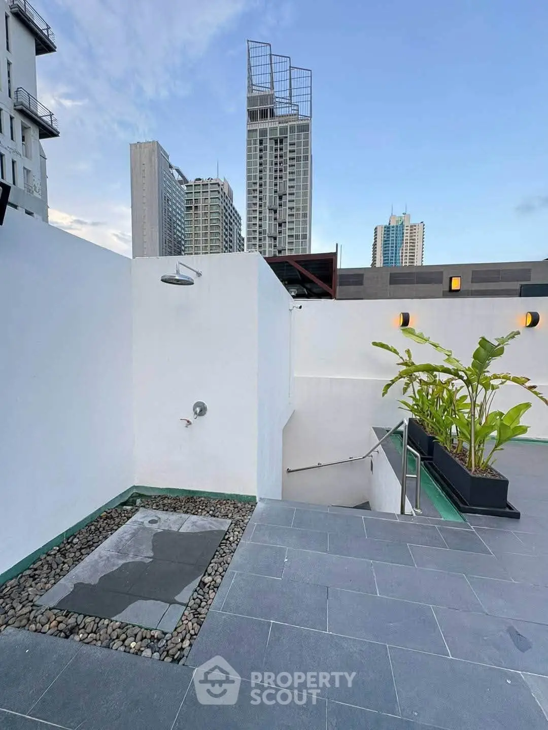 Modern rooftop terrace with city views and outdoor shower, perfect for urban living.