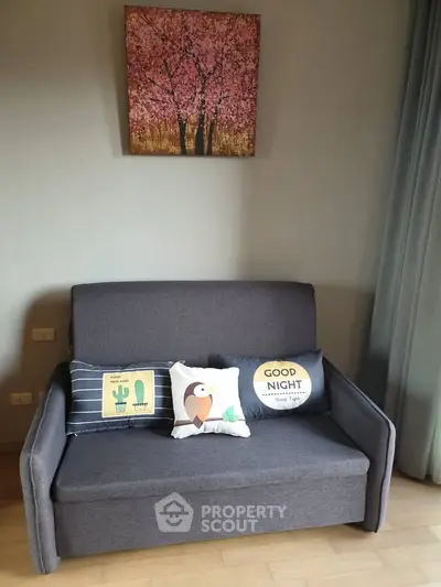 Cozy living room with modern gray sofa and decorative pillows under cherry blossom artwork.