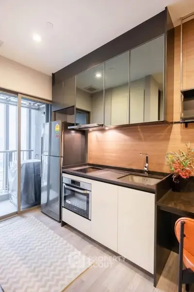 Modern kitchen with sleek cabinetry and balcony access in a stylish apartment.