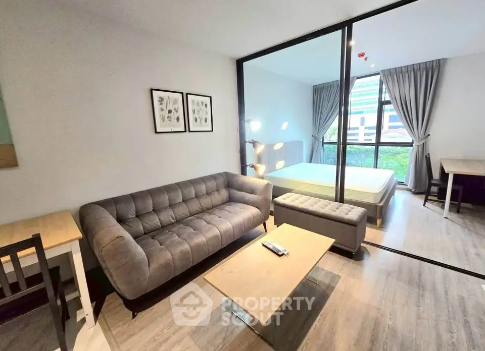 Modern studio apartment with stylish living area and cozy bedroom, featuring large windows and contemporary decor.