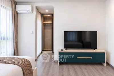 Modern bedroom with sleek TV stand and air conditioning, featuring a cozy ambiance and stylish decor.