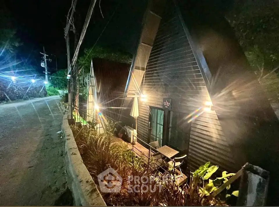 Charming A-frame cabin with cozy outdoor seating, nestled in a serene nighttime setting.