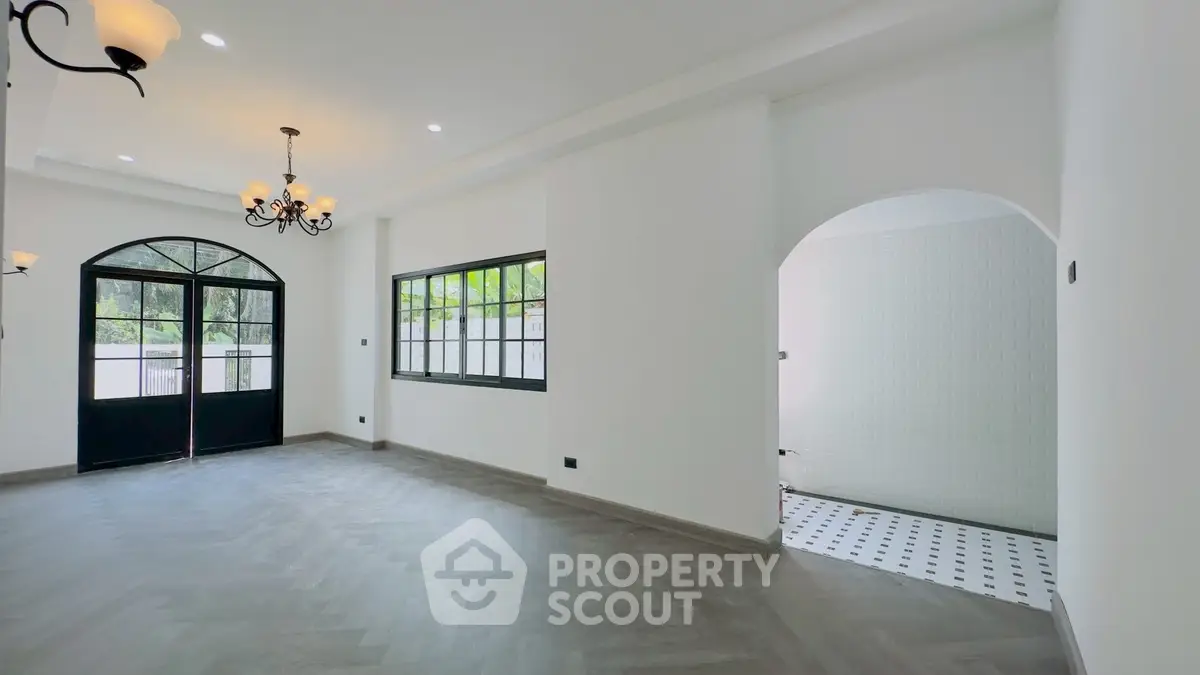 Spacious living room with elegant chandelier and large windows for natural light.