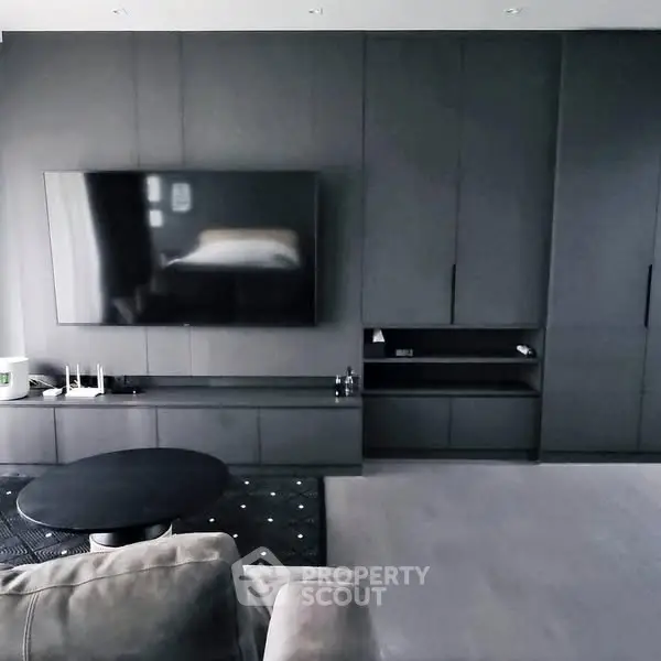 Modern living room with sleek black cabinetry and large flat-screen TV.