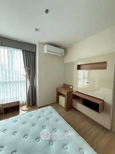Modern bedroom with natural light, featuring a minimalist design and air conditioning.