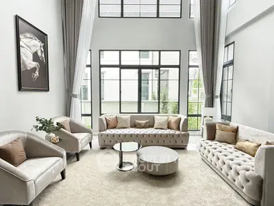 Luxurious living room with high ceilings, elegant sofas, and large windows offering natural light.