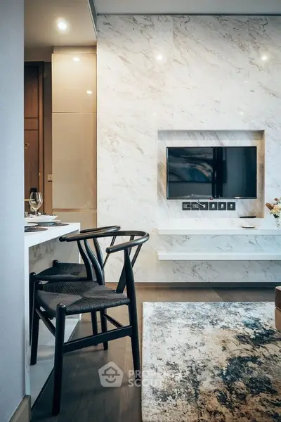 Modern living room with marble wall, mounted TV, and stylish chairs in a luxurious apartment.