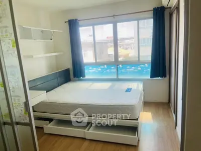 Bright bedroom with large window and modern furnishings in urban apartment.