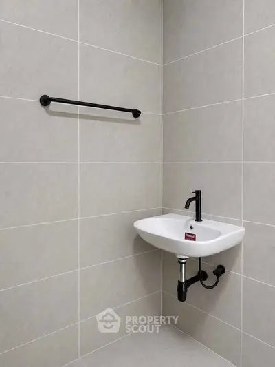 Modern minimalist bathroom with sleek wall-mounted sink and black fixtures.