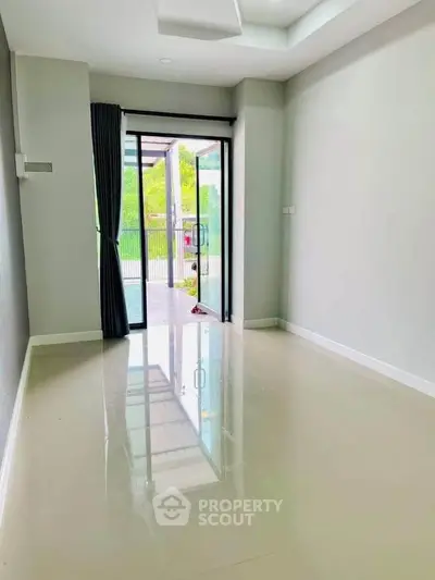 Spacious empty room with glossy floors and large sliding glass doors leading to a balcony with a view.