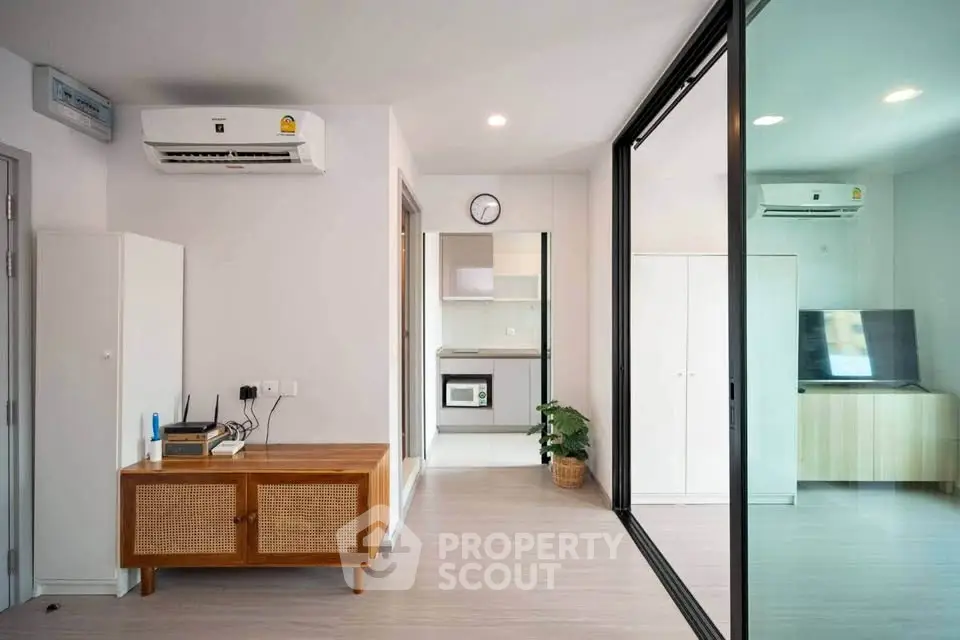 Modern open-layout living room with air conditioning and sleek kitchen view