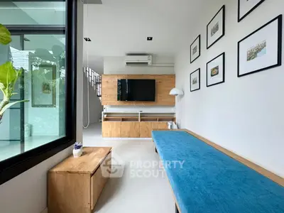 Modern living room with stylish wooden furniture and blue bench, featuring wall art and a flat-screen TV.