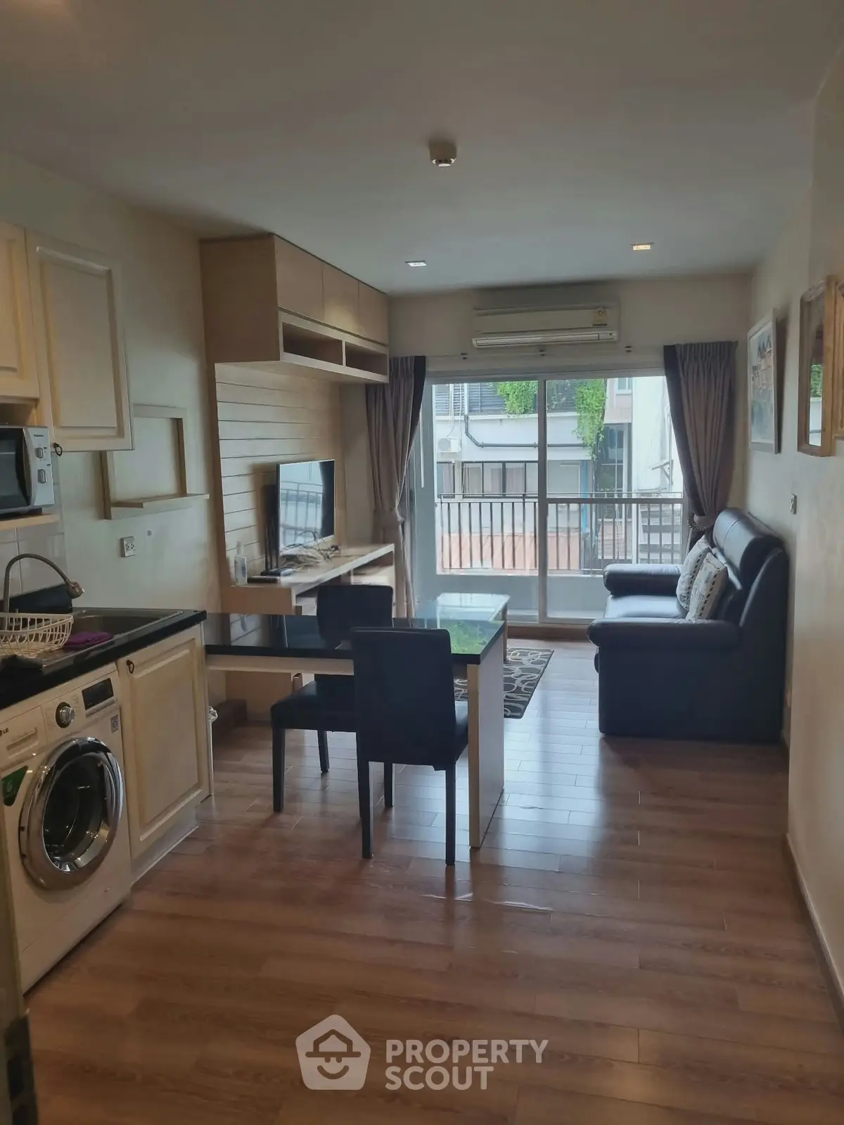 Modern living room with open kitchen, featuring a washing machine and balcony view.