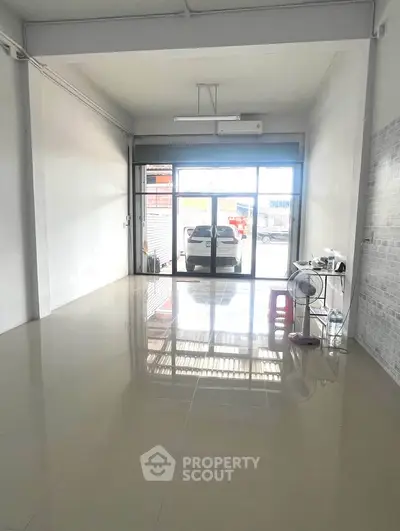 Spacious commercial space with large glass doors and ample natural light, ideal for retail or office use.