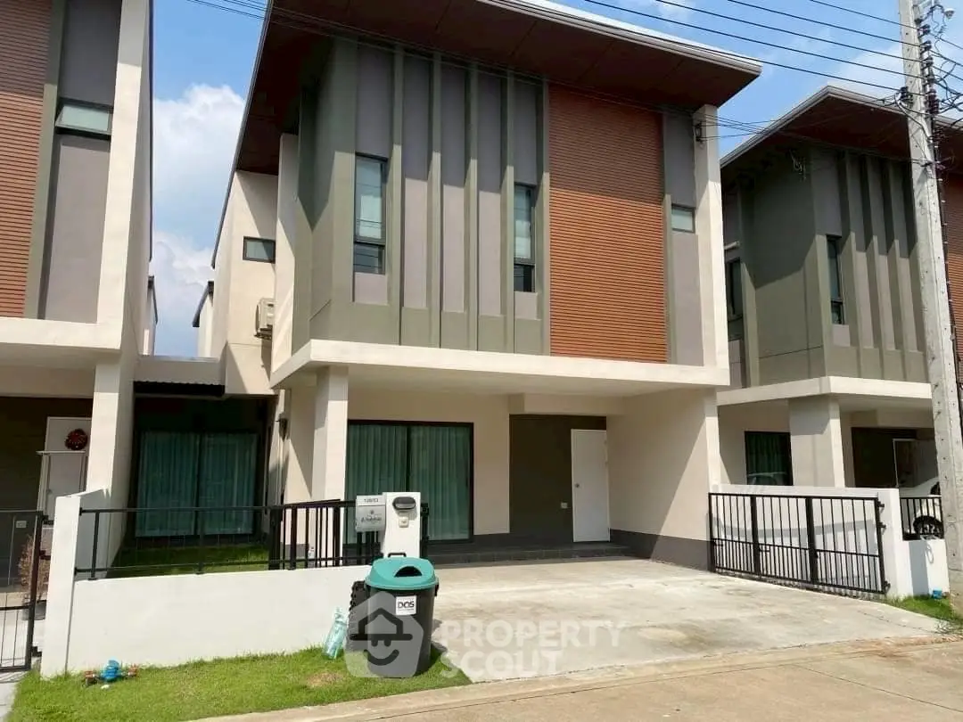 Modern two-story townhouse with sleek design and driveway in a suburban neighborhood.