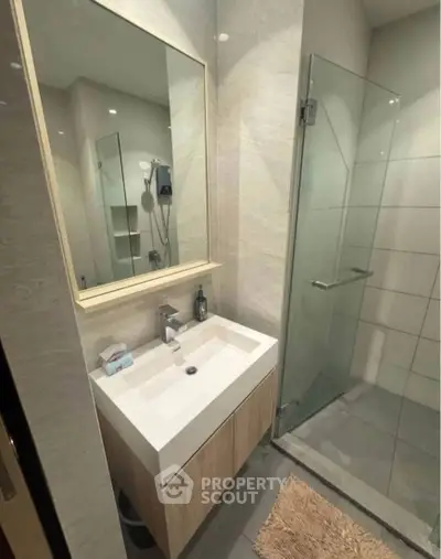 Modern bathroom with sleek glass shower and stylish vanity in contemporary apartment.