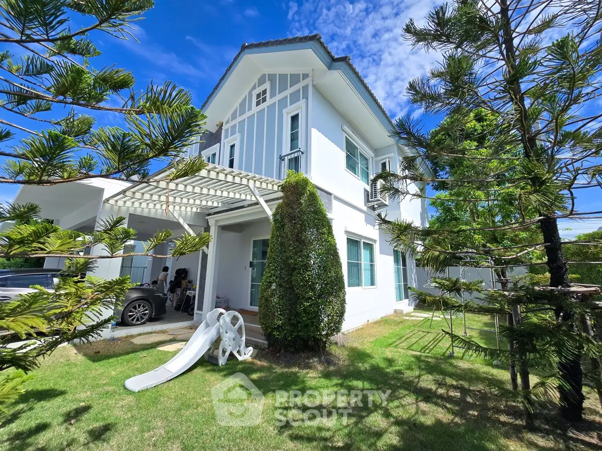 Charming two-story house with lush garden and playful slide, perfect for family living.