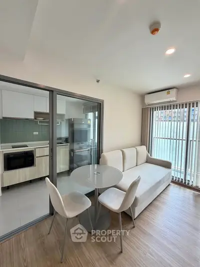 Modern living room with open kitchen and balcony view in a stylish apartment.
