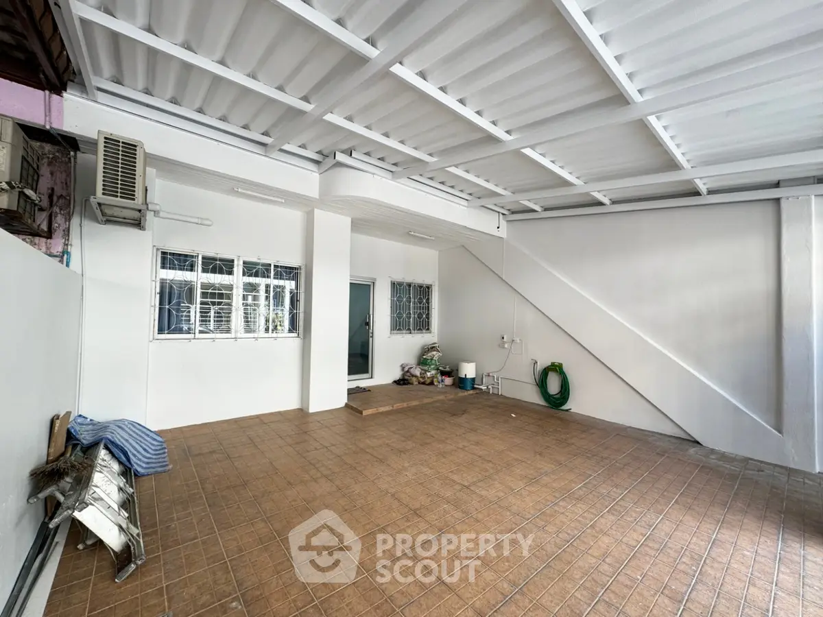 Spacious covered parking area with tiled flooring and air conditioning unit.