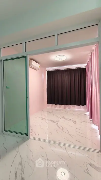Spacious modern room with marble flooring and large window, ideal for versatile living space.