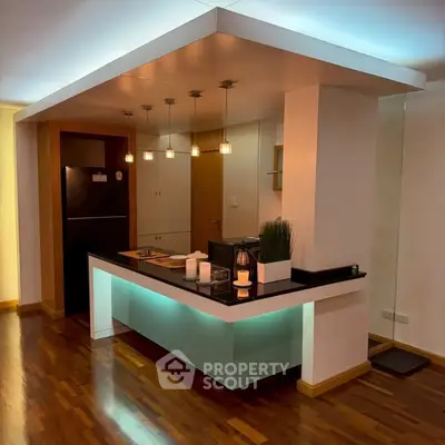 Modern kitchen with sleek design and ambient lighting, featuring a stylish island and hardwood floors.