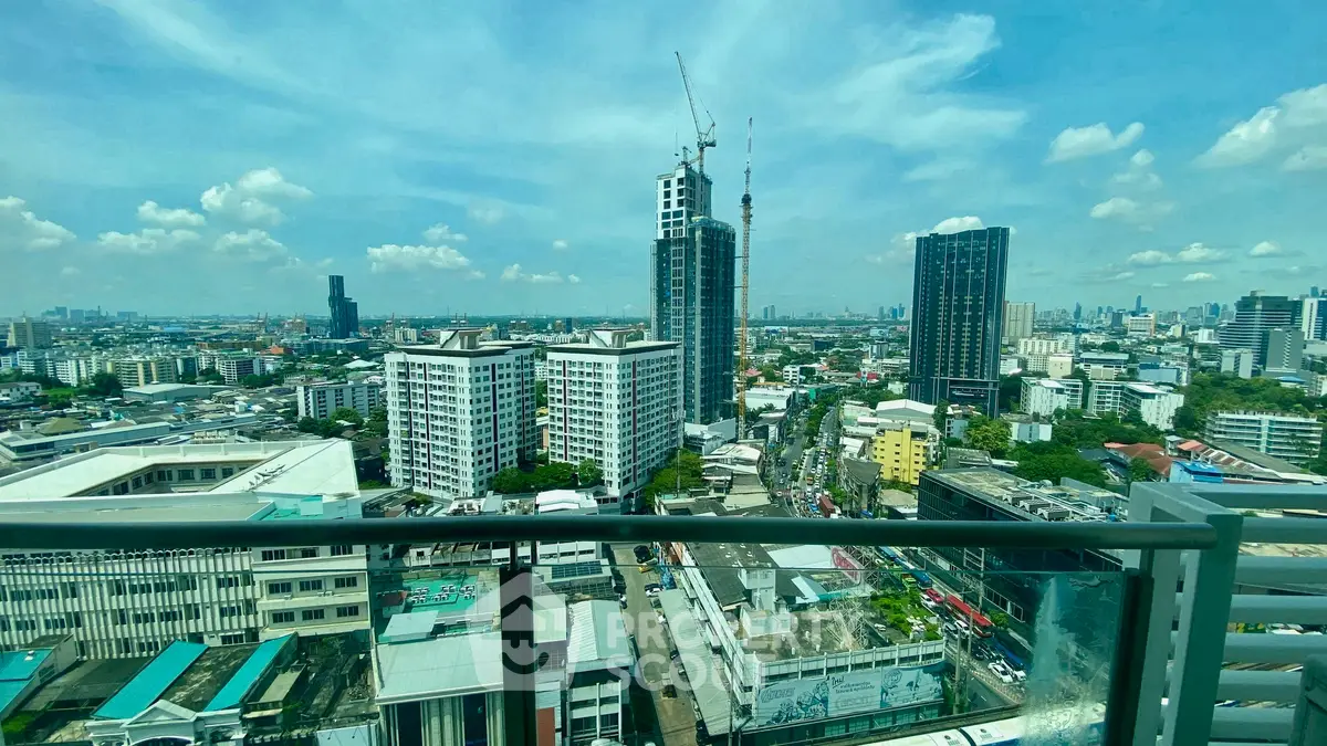 Stunning cityscape view from high-rise balcony with clear blue skies and urban skyline.