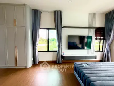 Modern bedroom with large window, stylish curtains, and sleek TV setup