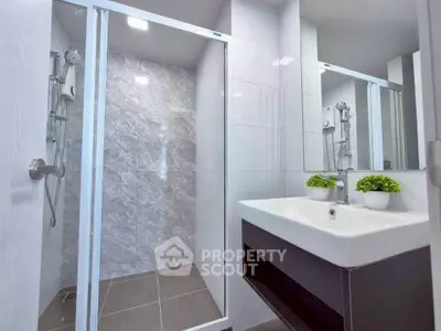 Modern bathroom with sleek shower and stylish sink, featuring elegant tile design and contemporary fixtures.
