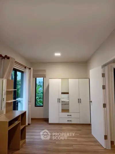 Spacious bedroom with modern wardrobe and large windows offering natural light.