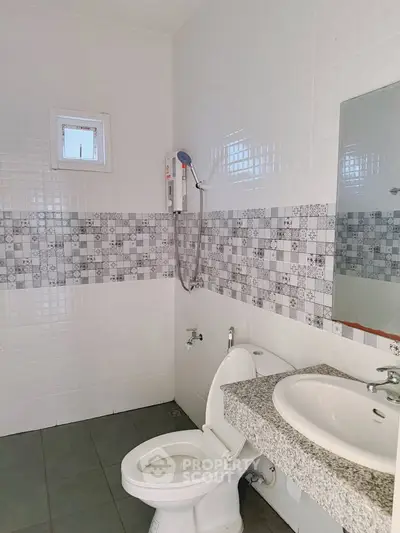 Modern bathroom with stylish tiles and essential fixtures in a contemporary home.