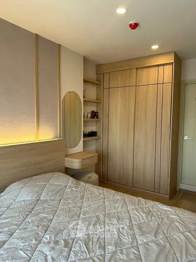 Modern bedroom with stylish wooden wardrobe and cozy bedding in a contemporary apartment.