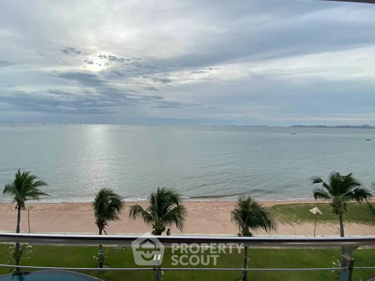 Stunning beachfront view from a balcony overlooking serene ocean waves and palm trees.