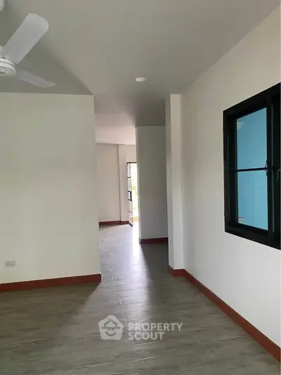 Spacious modern interior with wooden flooring and large window, perfect for natural light.