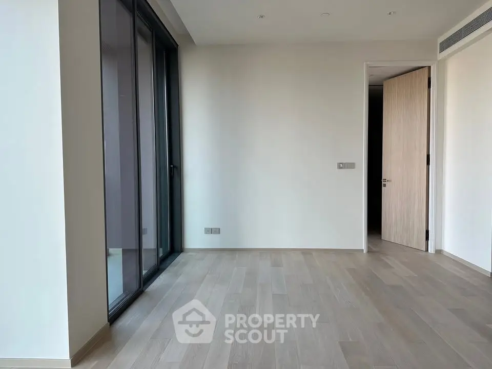 Spacious empty room with large windows and wooden flooring, perfect for customization.