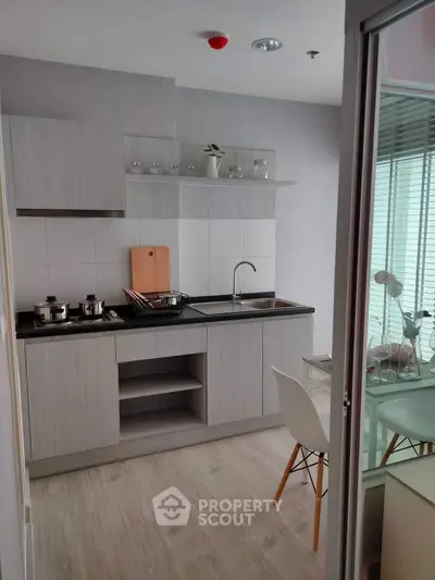 Modern kitchen with sleek cabinetry and dining area in stylish apartment.