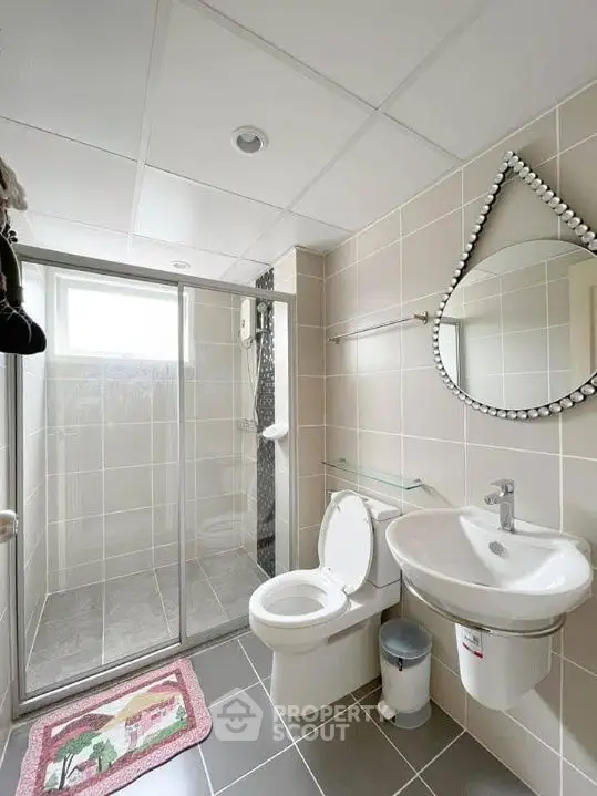 Modern bathroom with glass shower, stylish mirror, and sleek fixtures.