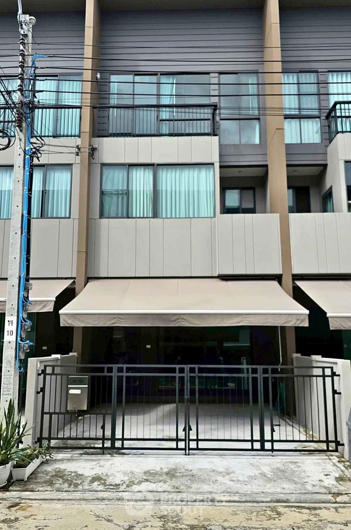 Modern townhouse exterior with gated entrance and large windows.