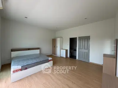 Spacious bedroom with modern furnishings and wooden flooring, perfect for comfort and style.