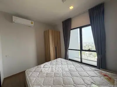 Spacious bedroom with large window offering stunning city views, featuring modern furnishings and ample natural light.