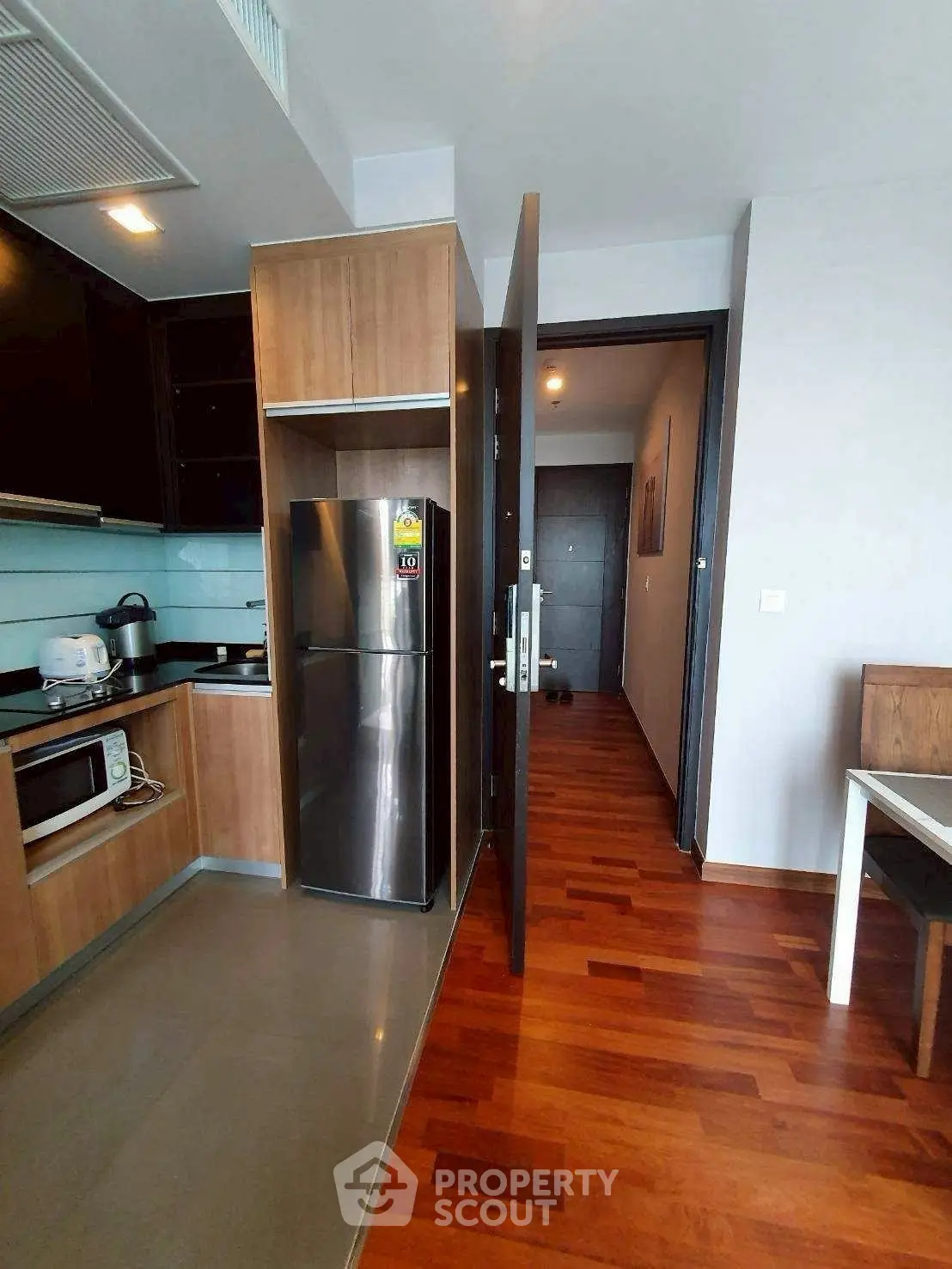Modern kitchen with stainless steel fridge and wooden flooring in a stylish apartment.