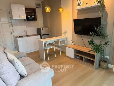 Modern living room with cozy sofa, wall-mounted TV, and compact kitchen area.