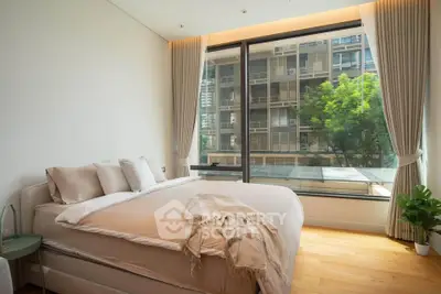 Spacious bedroom with large window offering a stunning city view, elegant decor, and natural light.