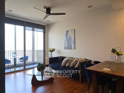 Modern living room with stylish decor and balcony view, featuring elegant furniture and natural light.