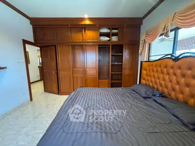 Spacious bedroom with elegant wooden wardrobe and luxurious bed in a stylish home.