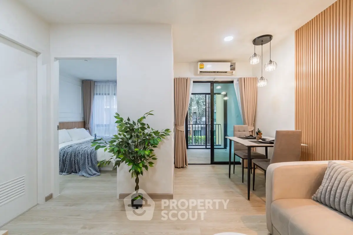 Modern living room with dining area and view of bedroom, featuring stylish decor and natural light.
