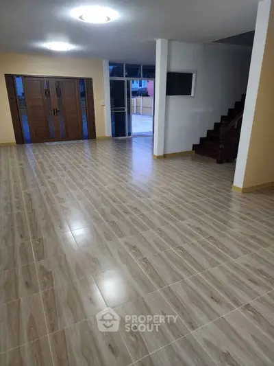 Spacious open-plan living area with wooden flooring and modern lighting.