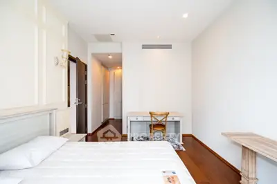 Spacious bedroom with elegant wooden flooring and a cozy study desk, perfect for a serene living experience.