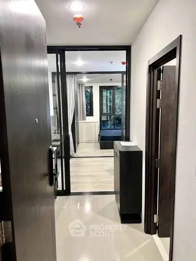 Modern apartment entrance with sleek hallway leading to a cozy bedroom and large windows.