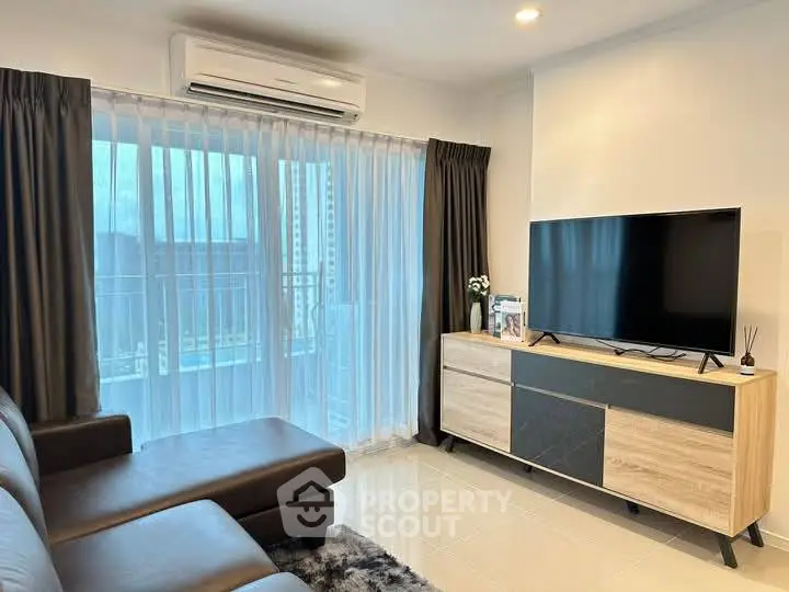 Modern living room with sleek furniture and large TV, featuring a balcony view.