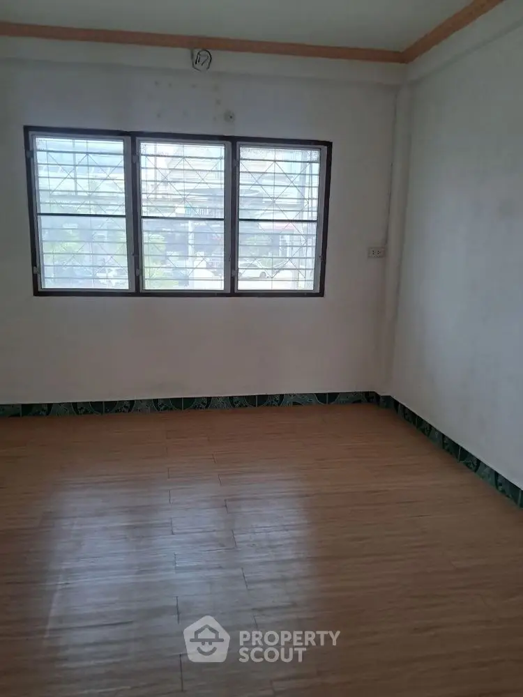 Spacious empty room with large windows and wooden flooring, perfect for customization.